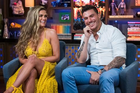 Brittany Cartwright Wearing Yellow Lace Dress While Sitting Next To Jax Taylor WearingWhite Shirt and Light Blue Pants On WWHL