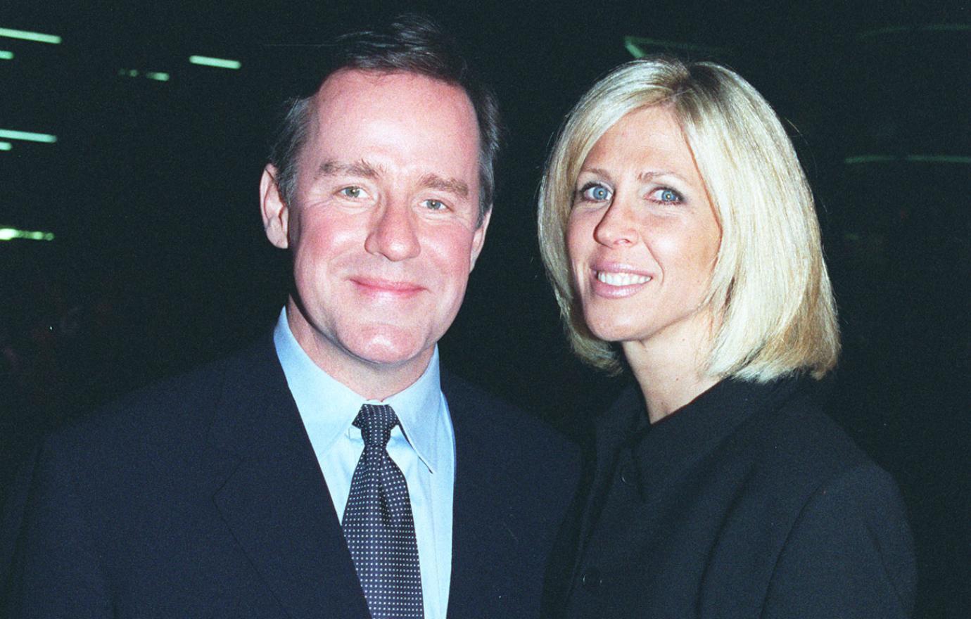 Phil Hartman, in a black suit and blue shirt, stands by his wife and killer Brynn Omdahl who wears all black.