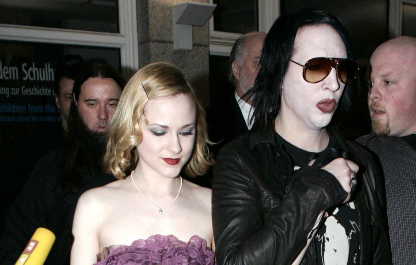 Marilyn Manson, in black, walks hand in hand with Evan Rachel Wood who wears a purple dress.