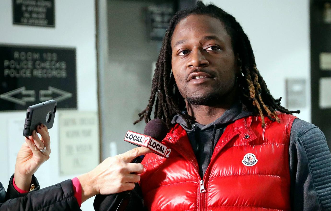 Adam Pacman Jones wears a red puffy vest and black shirt and talks to press.