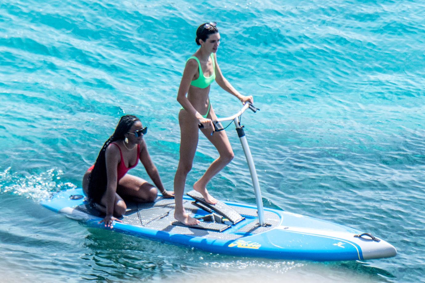 Kendall Jenner wears a neon-green bikini while having fun with friends paddle boarding in Mykonos.