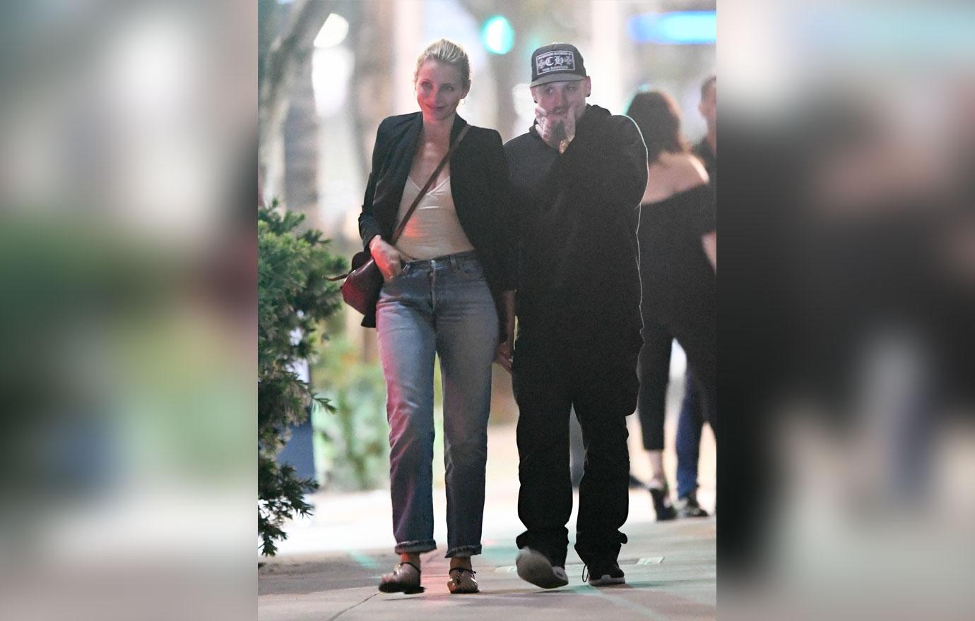 Cameron Diaz wears a black jacket and jeans. Benji Madden wears a black hoodie and cap.