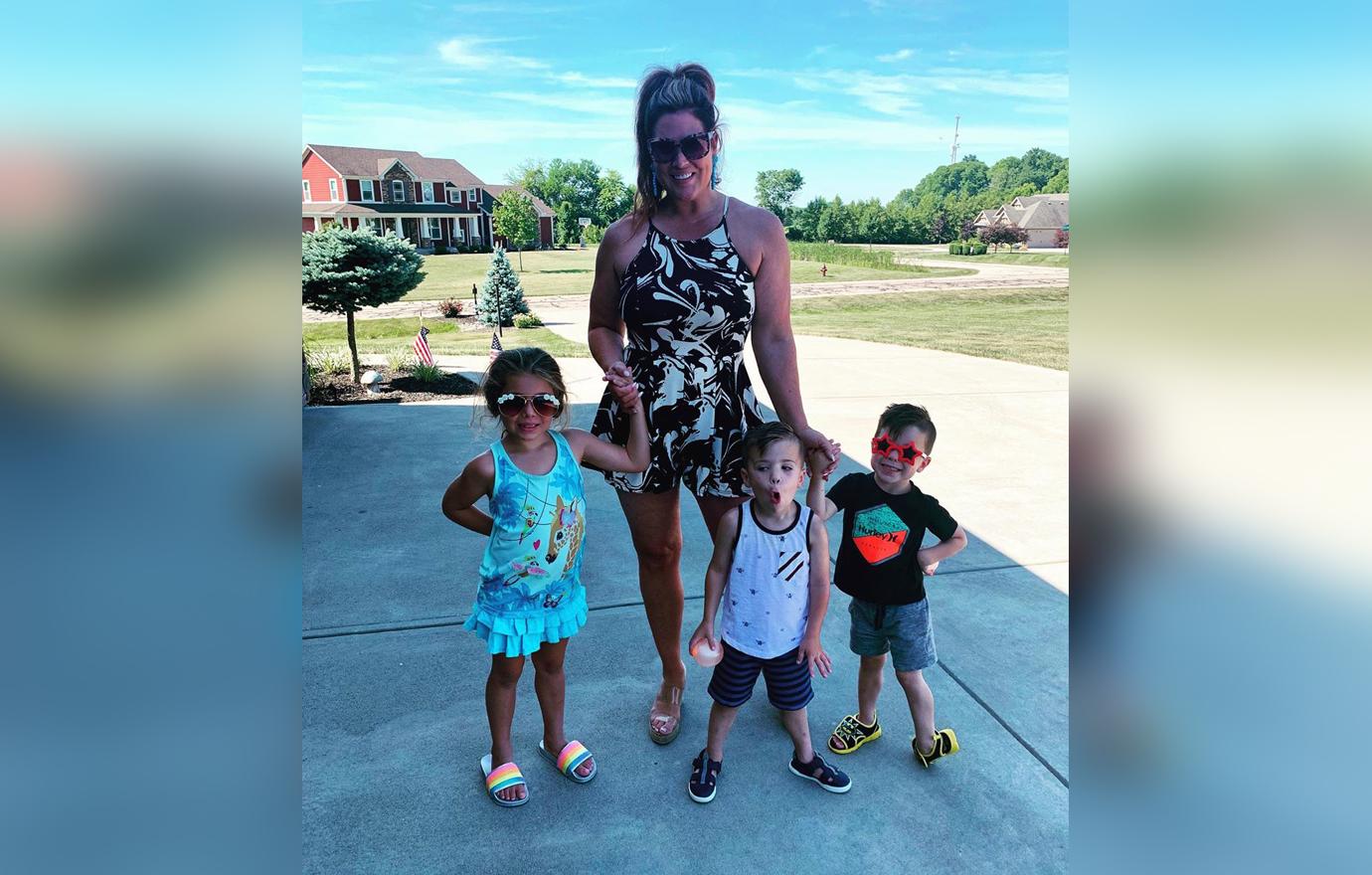 Emily Simpson Wearing Jumpsuit Outside Smiling With Three Children