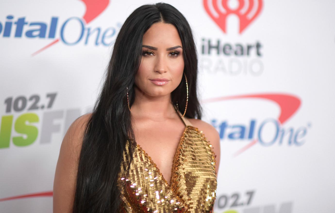 Demi Lovato posed for the cameras in a plunging neckline gold spaghetti strapped top.