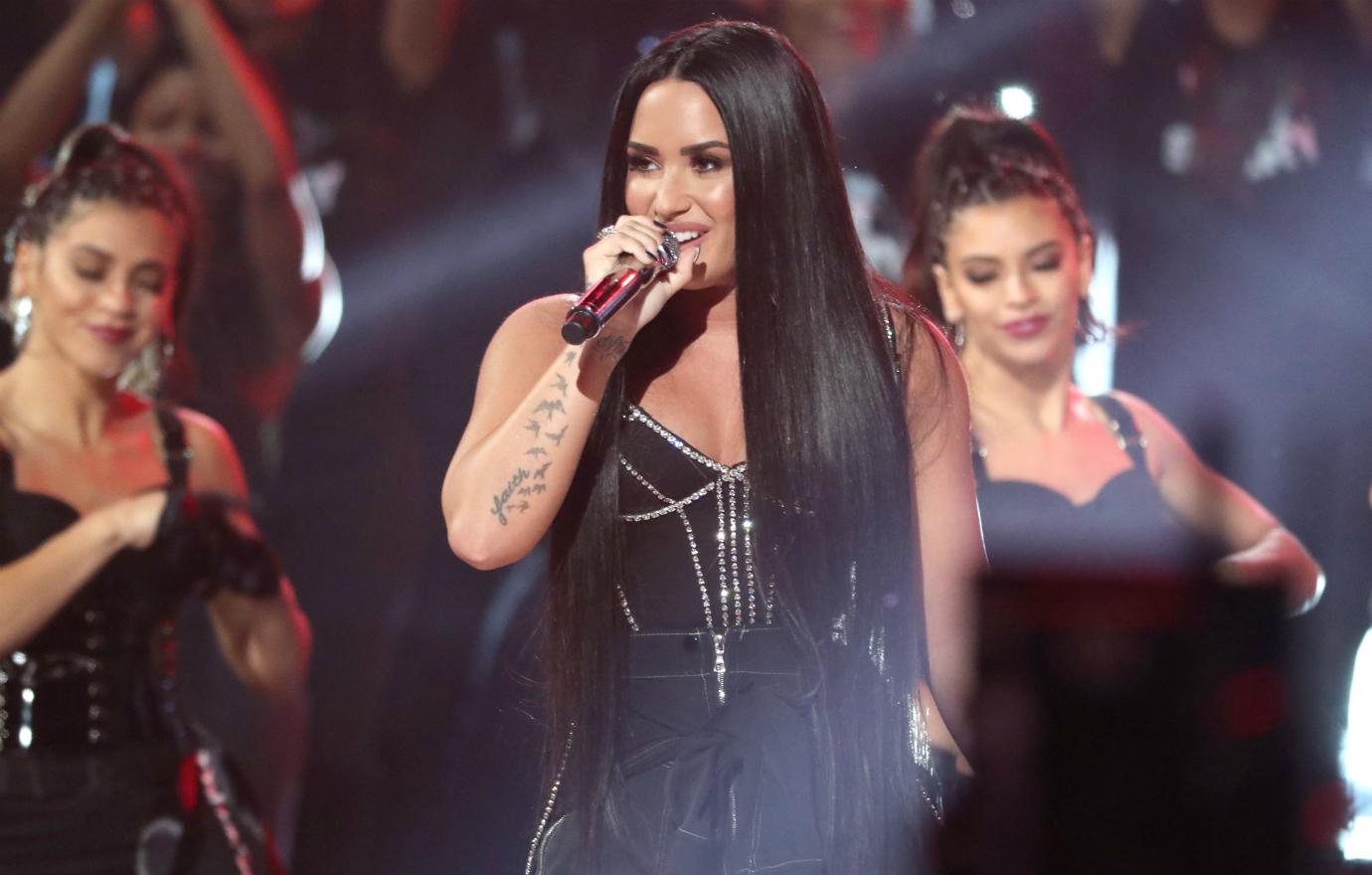 Demi Lovato performed in a black bustier that showed off her arm tattoos.