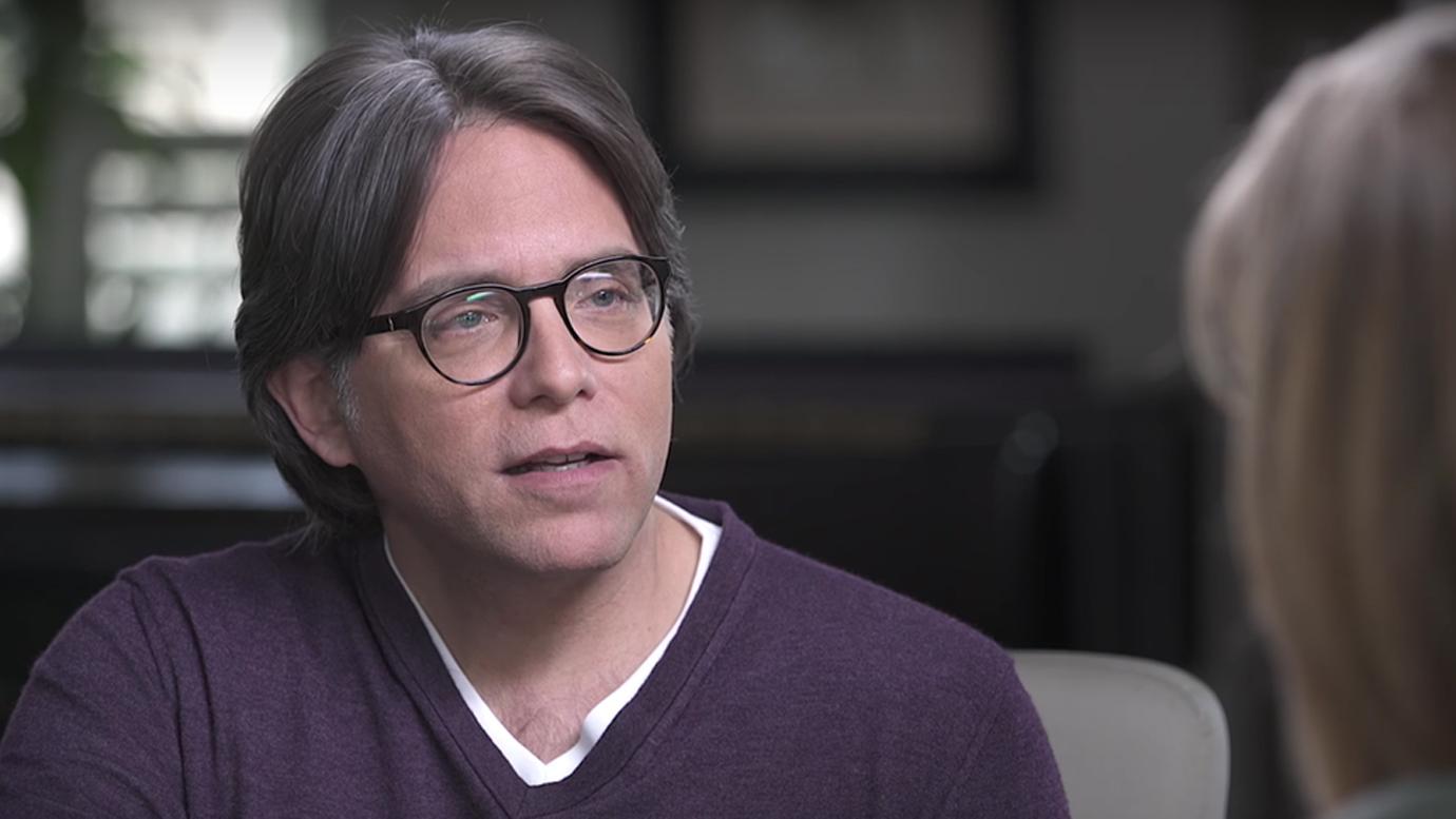 Keith Raniere Closeup Looking Serious in Purple Sweater and Glasses