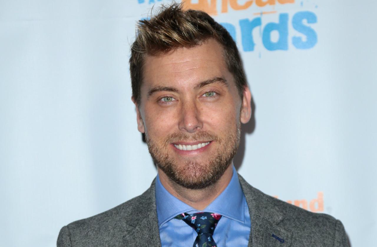 Lance Bass smiles in a gray suit and tie