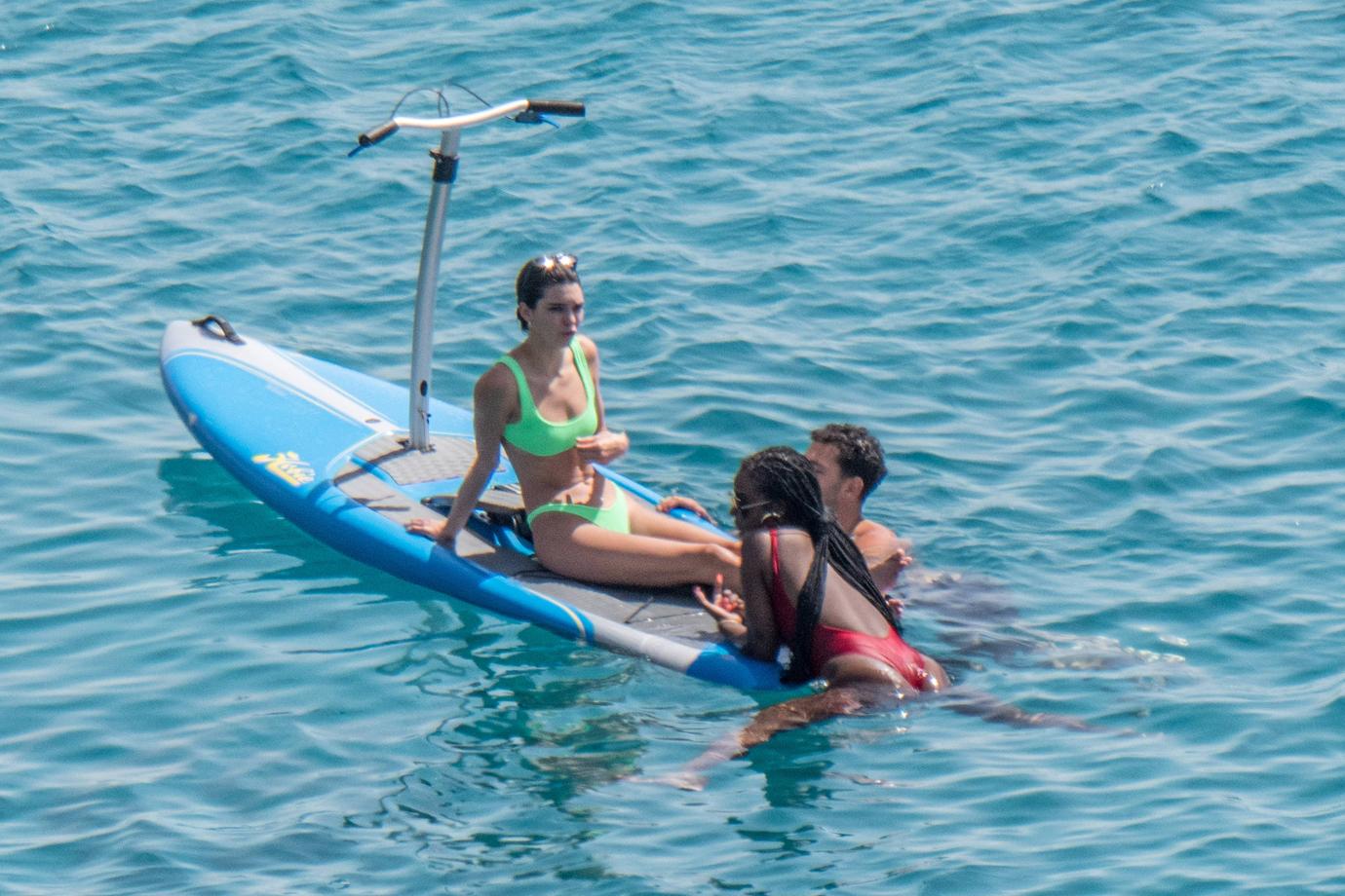 Kendall Jenner wears a neon-green bikini while having fun with friends paddle boarding in Mykonos.