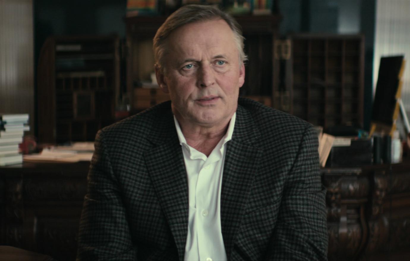 John Grisham spoke in a black blazer and a white dress shirt in a clip from the true crime documentary The Innocent Man.