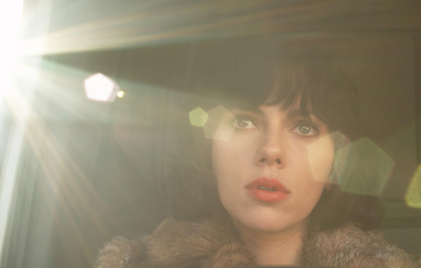 Scarlett Johansson, in black wig and red lipstick, gazed out a car window in Under the Skin.