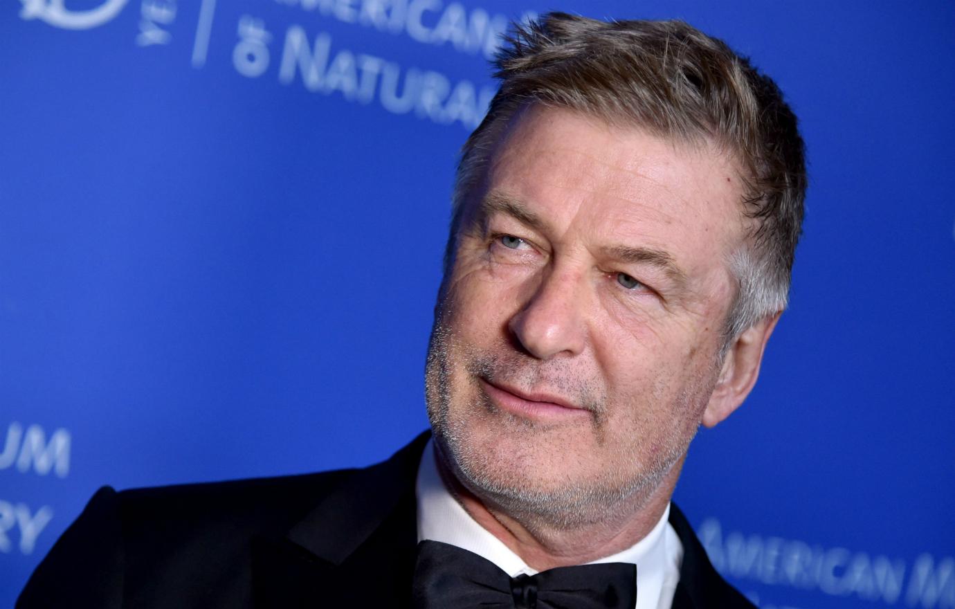 Alec Baldwin wears a black tux and white shirt on the red carpet.