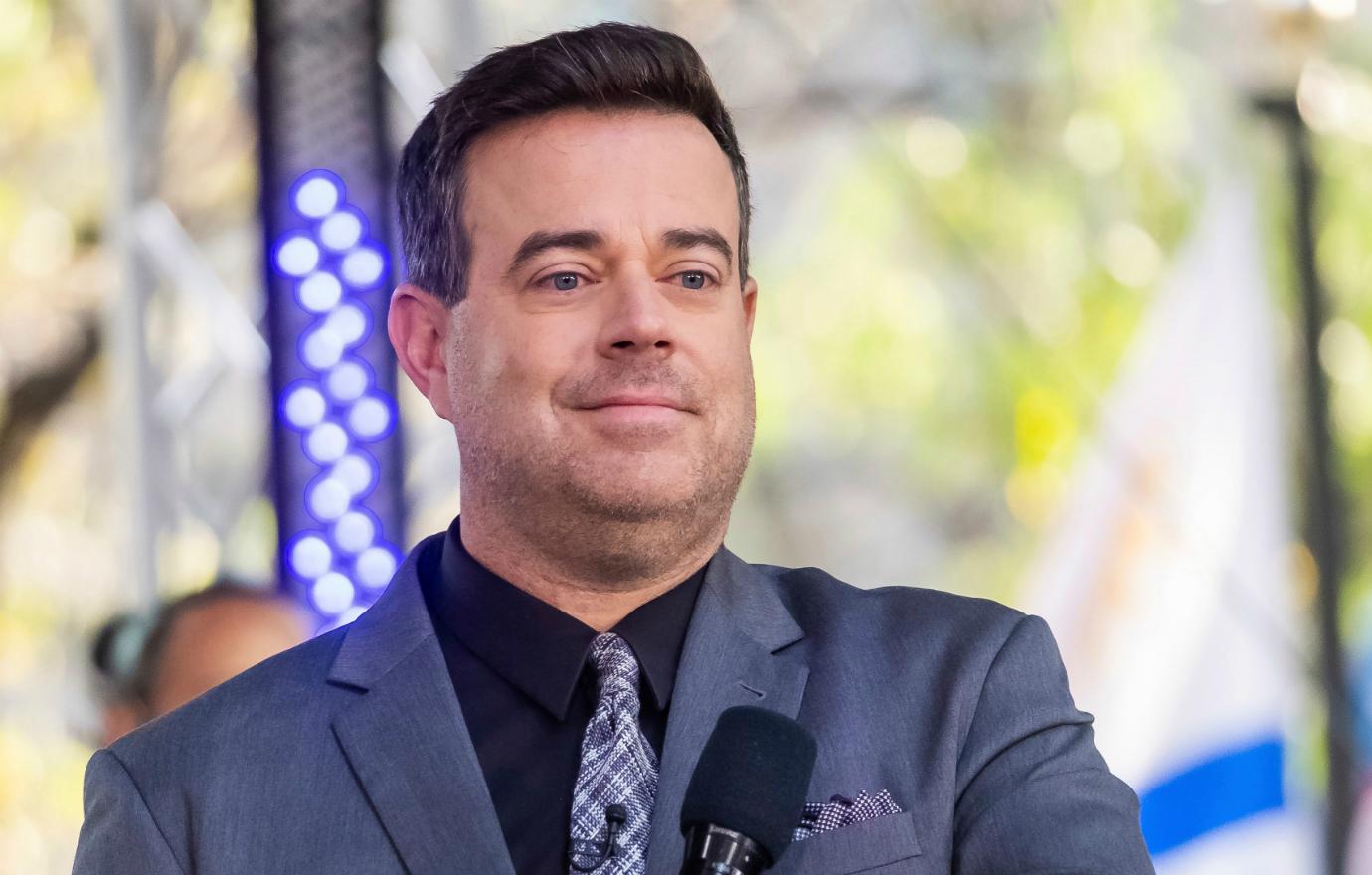 Carson Daly introduced a performer on the Today show and wore a grey suit with a black shirt and blue and grey tie.