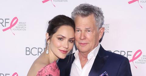 Katharine McPhee Smiling In Pink Dress Being Held By A Smiling David Foster In A Navy Suit