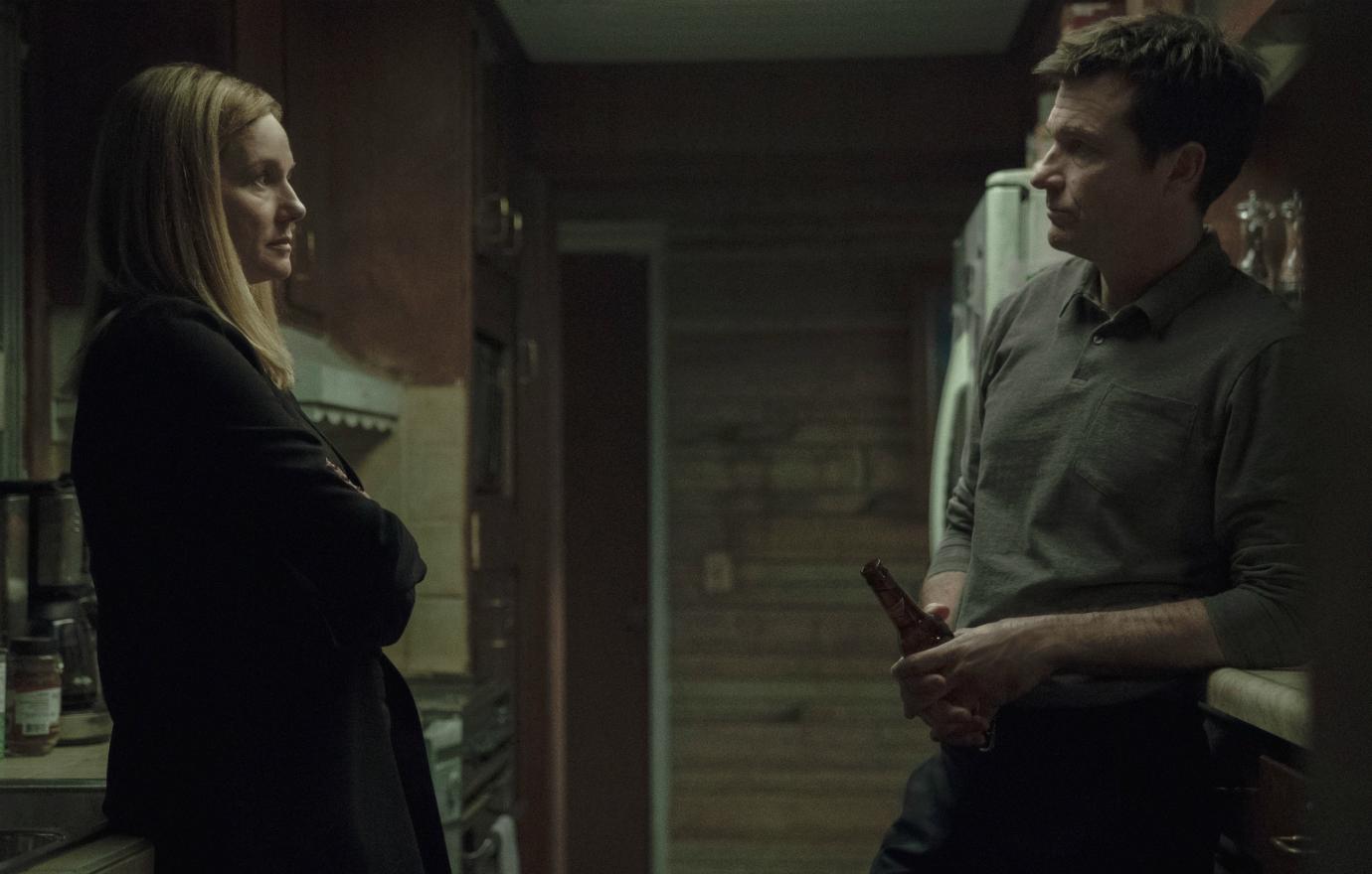 Jason Bateman wore an olive casual collared shirt and grey slacks, as Laura Linney stared back at him in all black in a scene from Ozark.