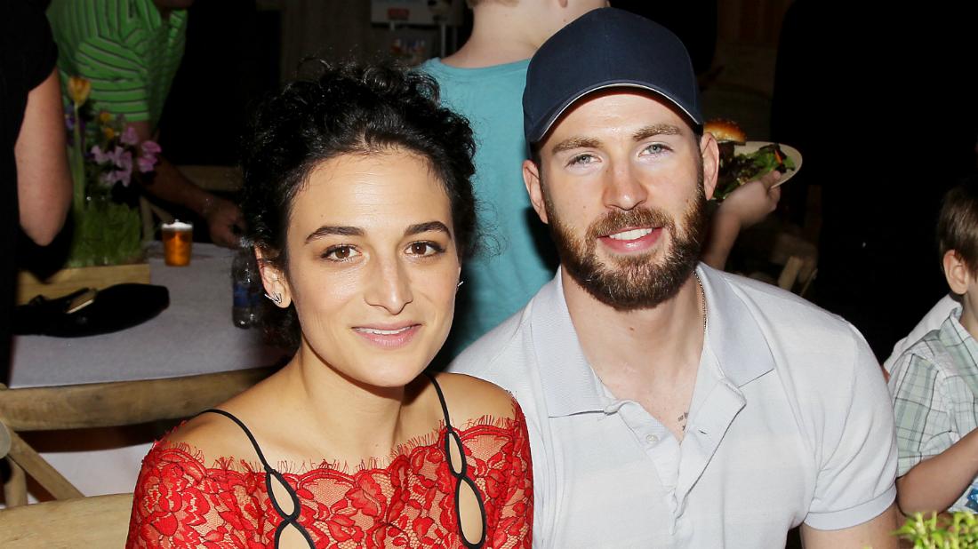 Jenny Slate wore a red dress with black spaghetti straps while Chris Evans donned a white Izod and a blue baseball hat.