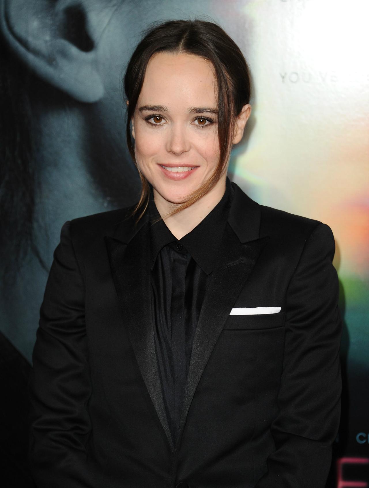 Ellen Page wears a black jacket and black tuxedo shirt with a white pocket square, hair in an updo.