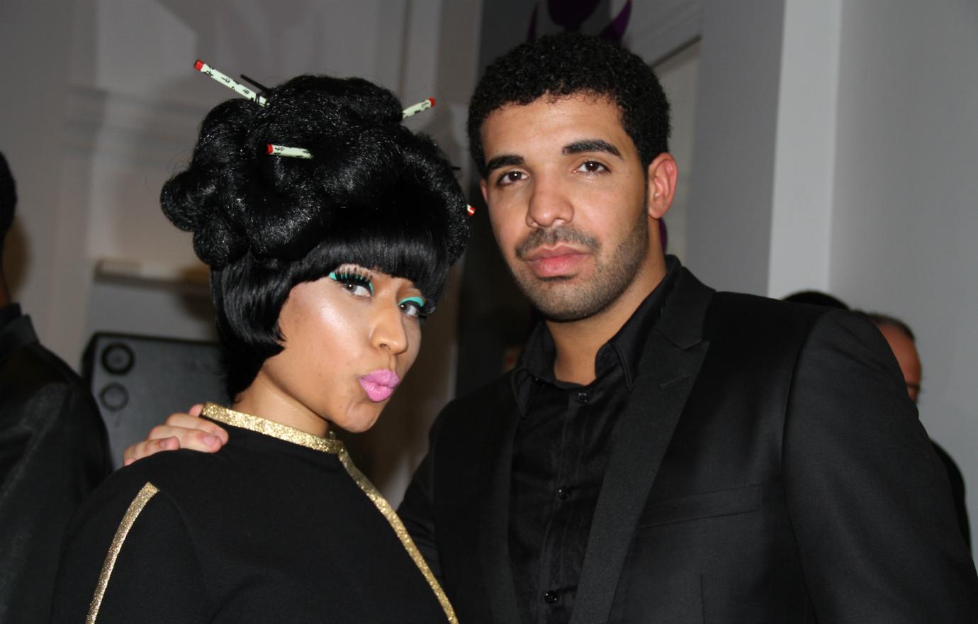 Nicki Minaj, dressed up in a 60's hairstyle, stands next to Drake who's all in black.