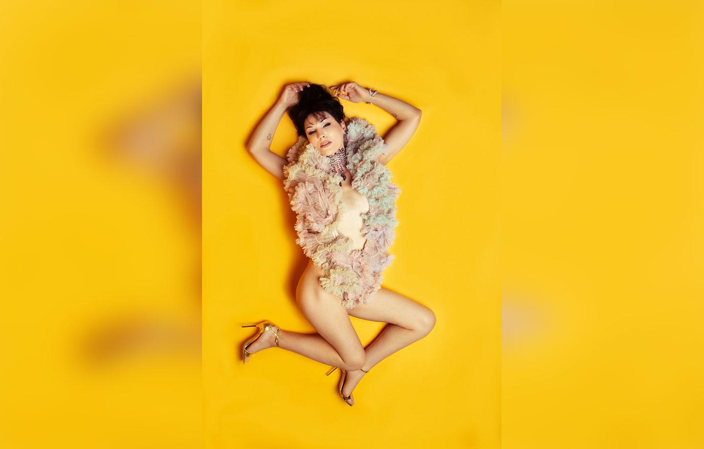 Trans Model Plastic Martyr Lying on Yellow Background Wearing Only Jewelry and Ruffled Boa