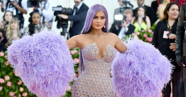 Kylie Jenner wears huge lilac pom-pom sleeves, a transparent, off-the-shoulder patterned dress and poses on the red carpet.