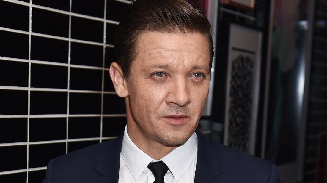 Jeremy Renner Wearing Black Tie and Dark Blue Suit With White Shirt