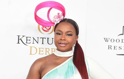 Phaedra Parks wears a choker, pink hat, and dress on a red carpet.
