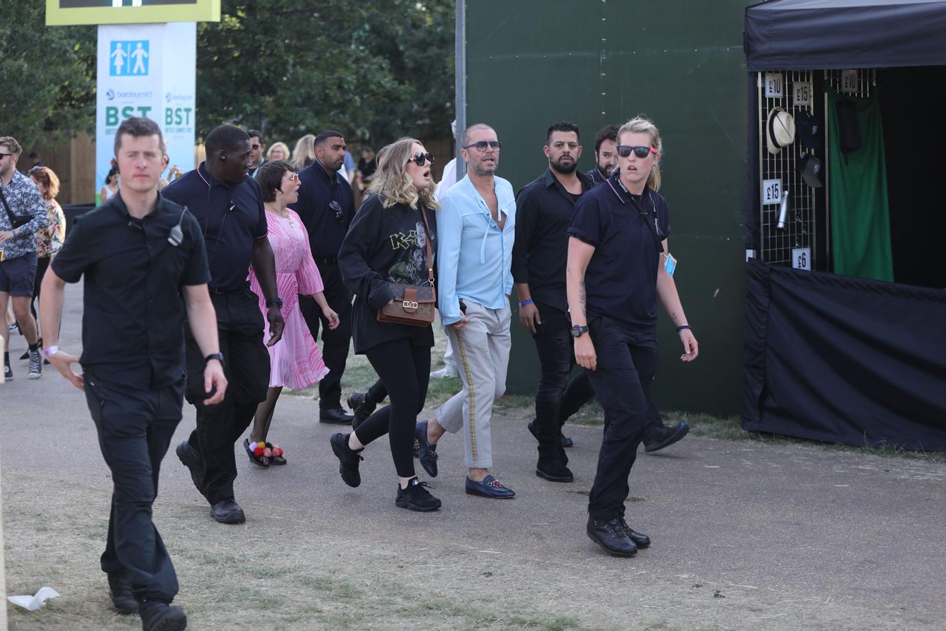 Adele is seen surrounded by bodyguards while holding hands with a male friend in Hyde Park, London, where Celine Dion was headlining.