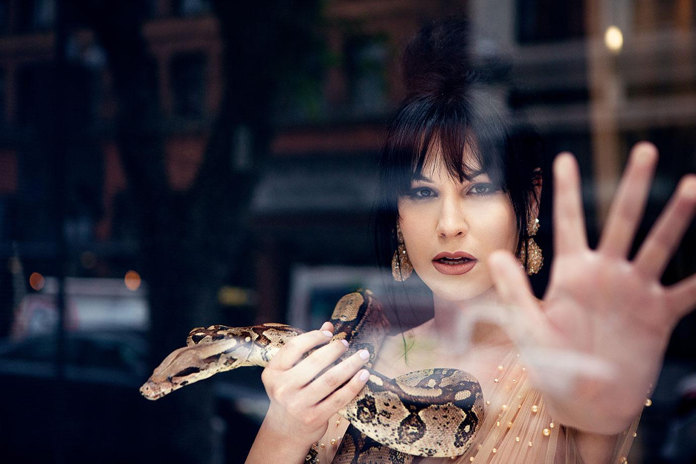 Trans Model Plastic Martyr With Hand Up Against Window In Pearl Studded Sheer Dress Holding Snake