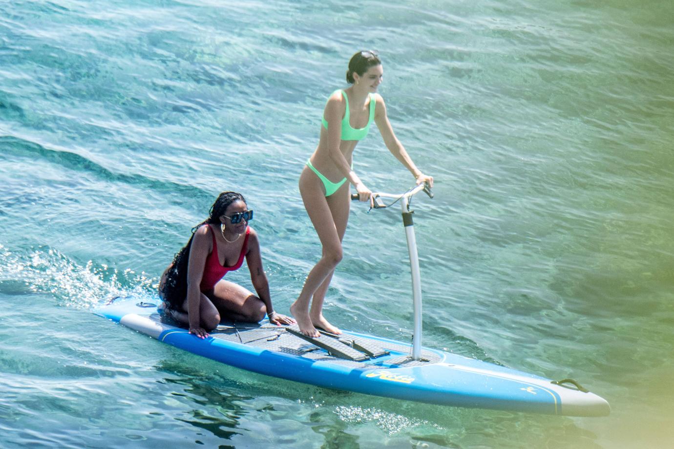 Kendall Jenner wears a neon-green bikini while having fun with friends paddle boarding in Mykonos.