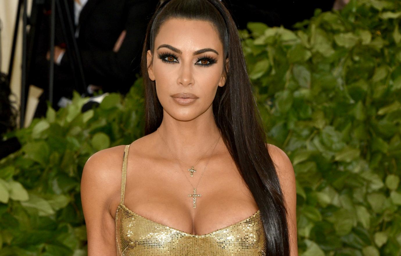 Kim Kardashian wears a golden shimmering spaghetti strap dress and long hair at the 2018 Met Gala.