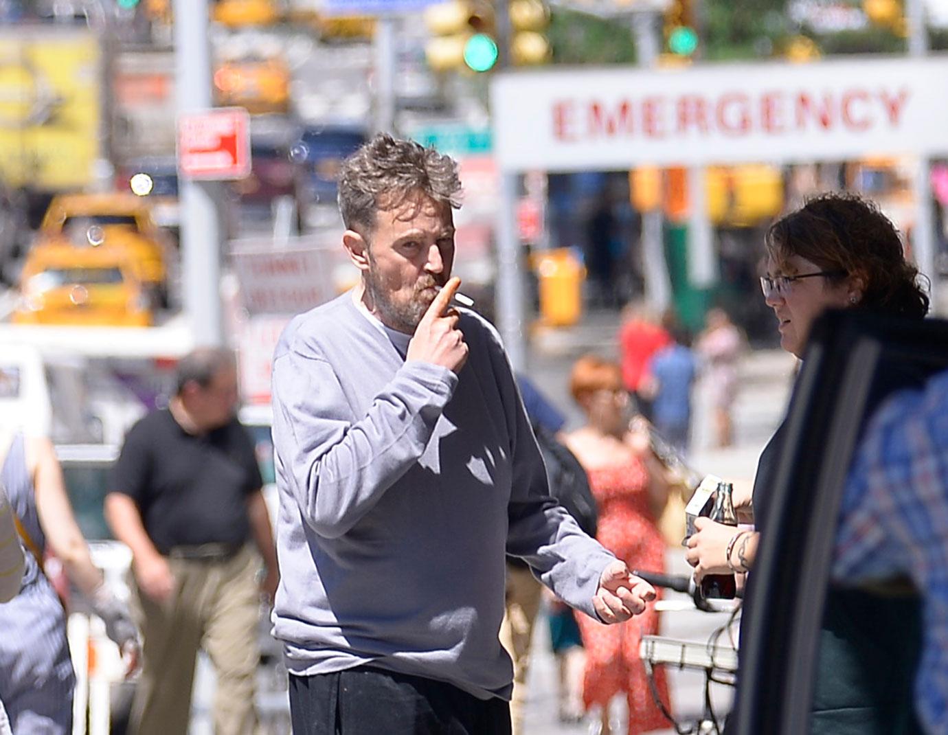 Matthew Perry Wearing Grey Top Smoking a Cigarette On A NYC Street In Font Of Hospital