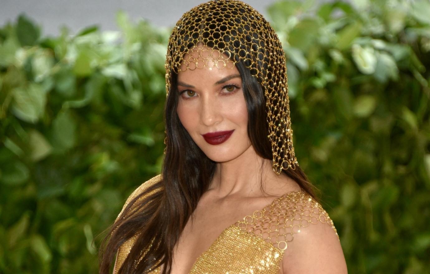 Olivia Munn wears a gold dress and matching headpiece at the 2018 Met Ball.