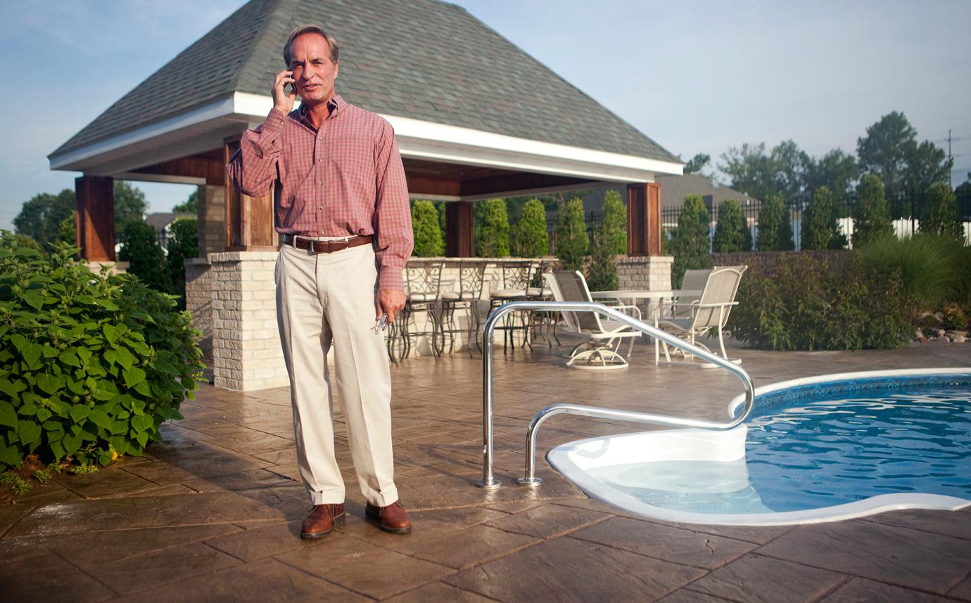 Chris Cline On Phone Near Pool Outside Dressed in Trousers and Button Down