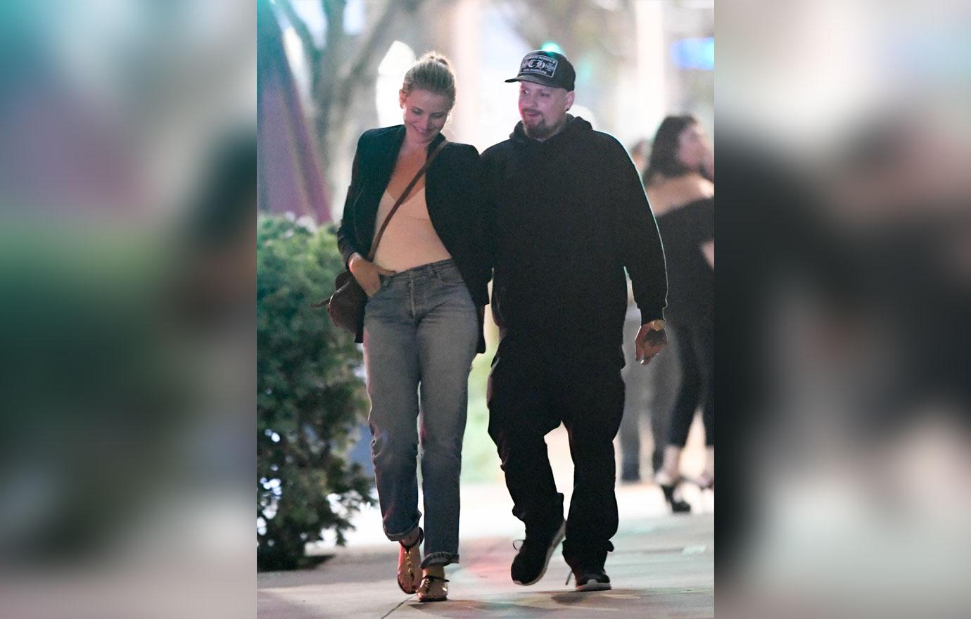 Cameron Diaz wears a black jacket and jeans. Benji Madden wears a black hoodie and cap.