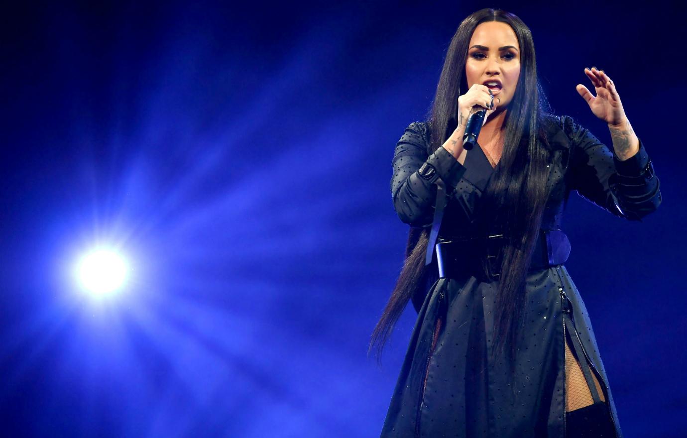 Demi Lovato performed on stage in a black overcoat that covered everything, except the hint of a thigh slit.