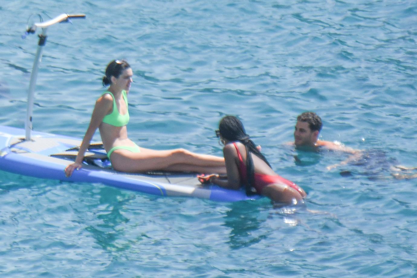 Kendall Jenner wears a neon-green bikini while having fun with friends paddle boarding in Mykonos.