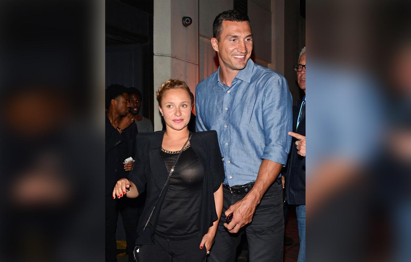 Hayden Panettiere Wears Sheer Black Shirt and Large Shoulder Pad Jacket With Small Pregnancy Bump Looking Uncertain as Wladimir Klitschko Walks Closely Behind Her Smiling To Someone Off Frame