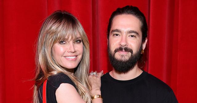 Heidi Klum Tom Kaulitz Smiling And Embracing In Front Of A Red Curtain