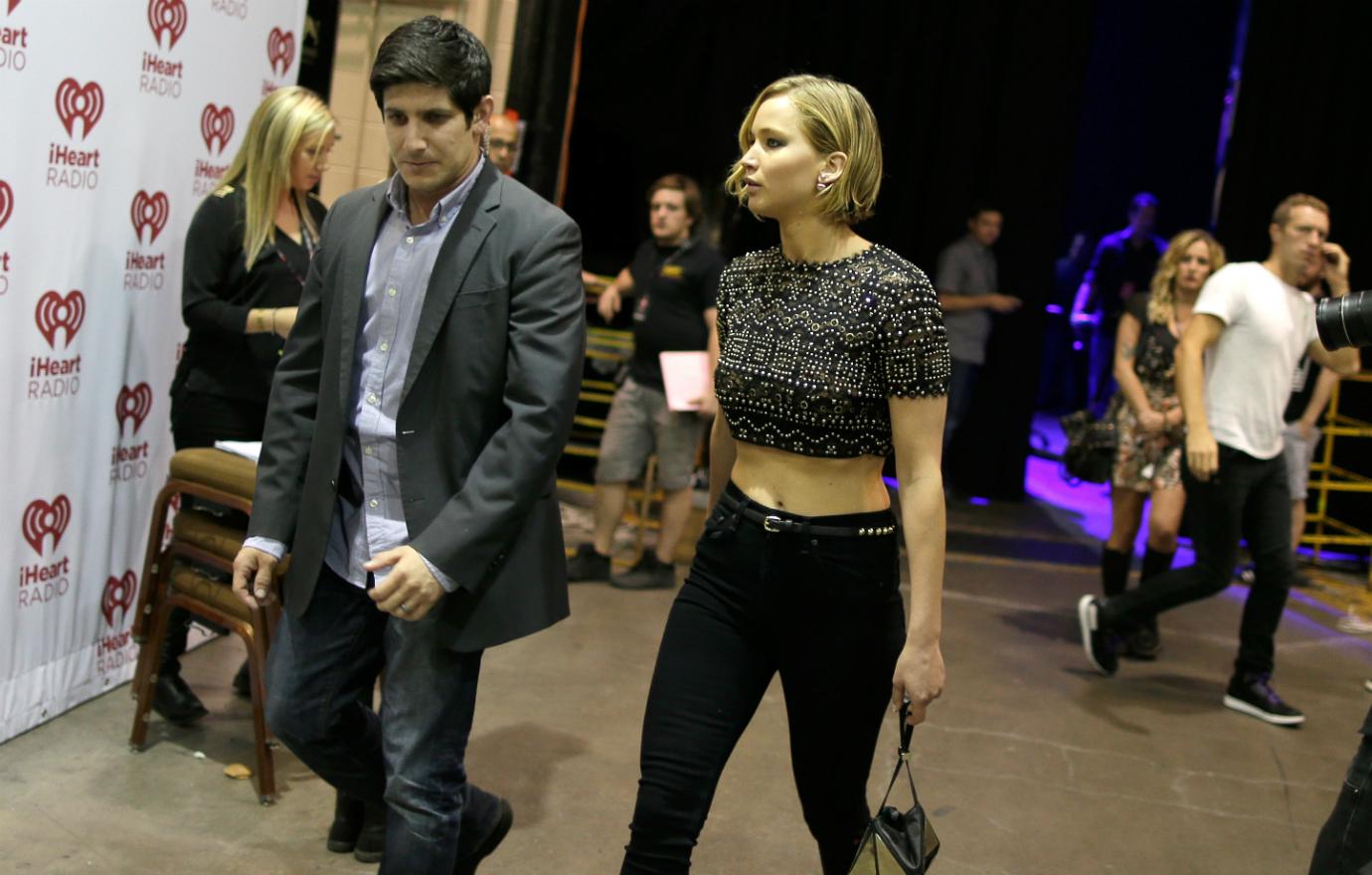 Jennifer Lawrence backstage in a navel-bearing black and silver top with skin-tight black jeans and black high heels while Chris Martin wore a white T-shirt and jeans.