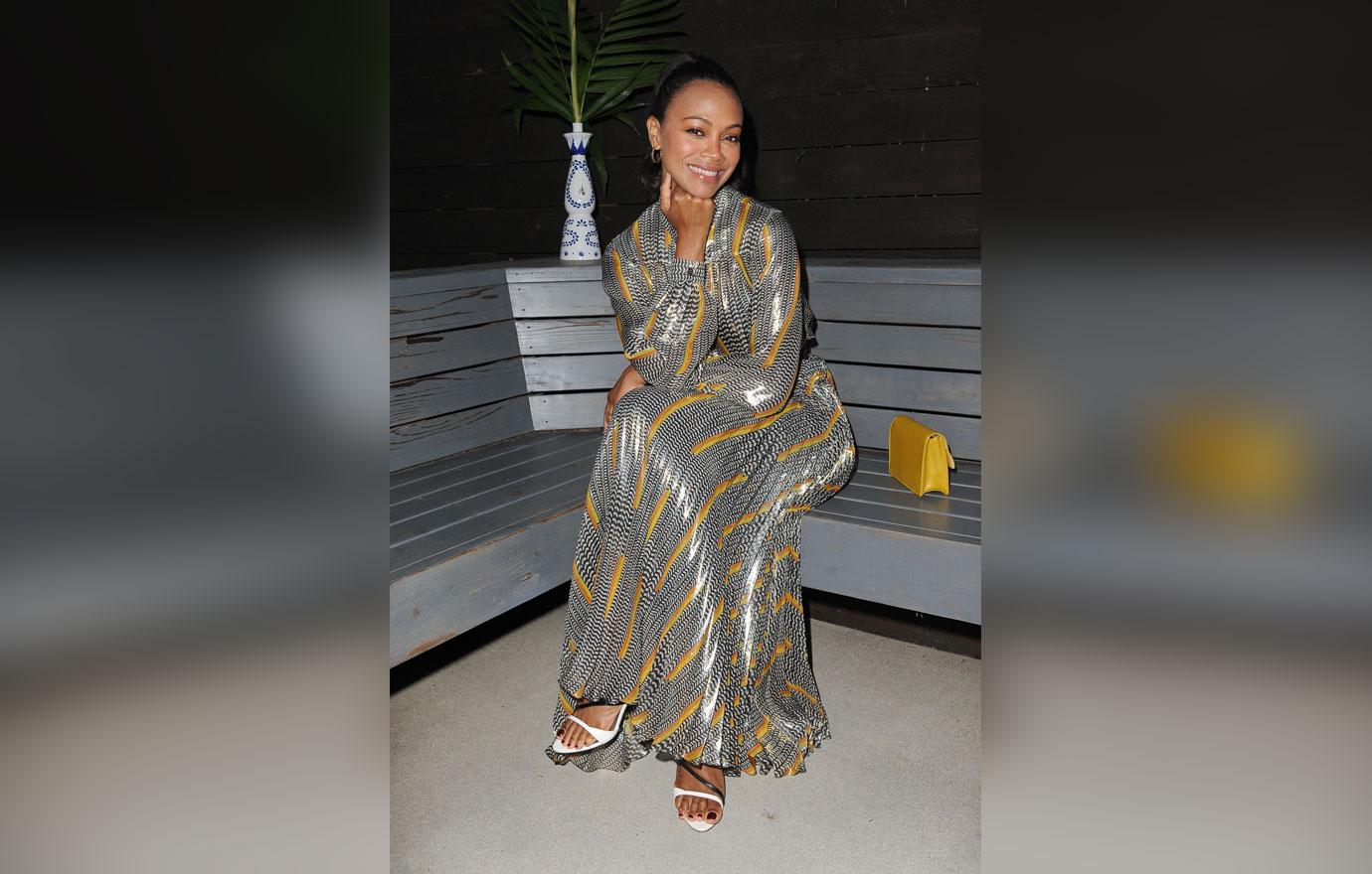 Zoe Saldana Wearing Black, White, Yellow and Orange Print Dress Sitting On Bench Outside Deck