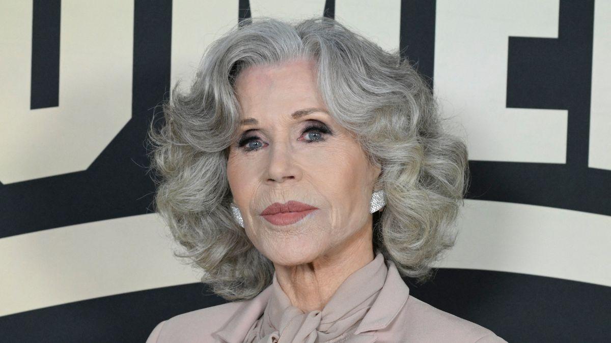 Image of Jane Fonda arrived at LAX in a wheelchair, assisted by airline staff.