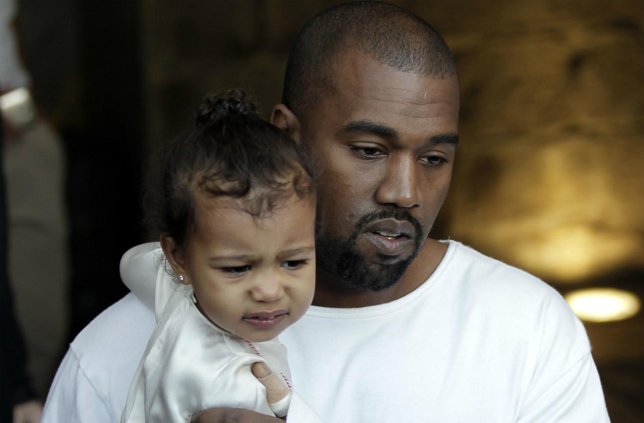 US rapper Kanye West, husband of US reality TV star Kim Kardashian, carries their daughter North, following a reported baptism ceremony at the Armenian St. James Cathedral in Jerusalem's Old City on April 13, 2015