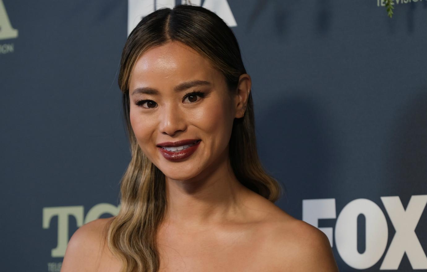 Jamie Chung smiles on the red carpet in an off-the-shoulder dress.