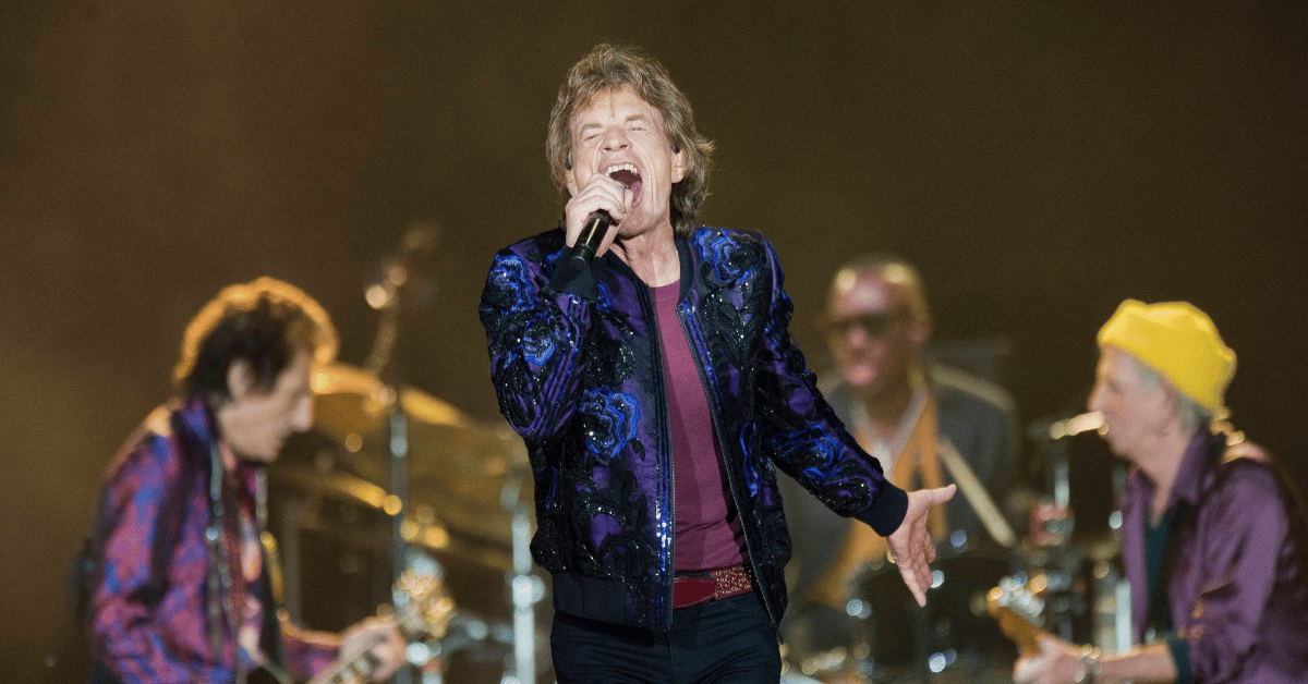 Photo of Mick Jagger performing in blue jacket. 