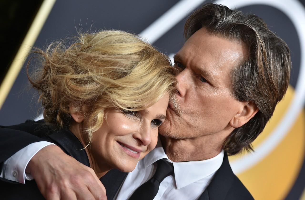 Kevin Bacon in a suit, kisses Kyra Sedgwick on the red carpet