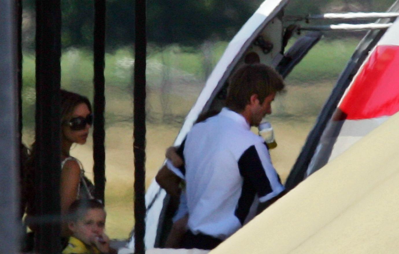 David Beckham in a white shirt and a baby bottle in his mouth boards a plane with Victoria and son Brooklyn right behind him.