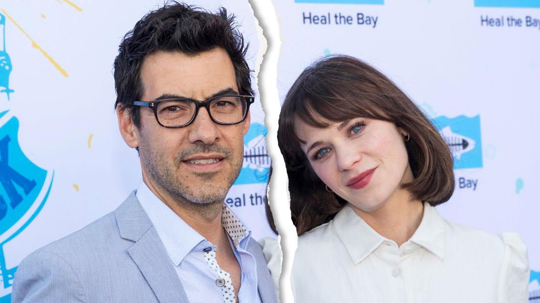 Jacob Pechenik Wearing Glasses, Blue Shirt And Suit With Zooey Deschanel Wearing White Blouse Standing In Front Of SAVE THE BAY Step And Repeat