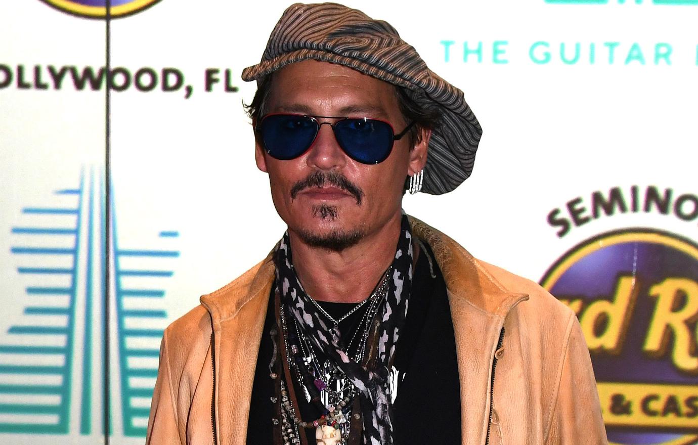 Johnny Depp rocked a light peach leather jacket with a black T-shirt underneath, accessorized with a flop hat and an intertwining scarf and necklaces.