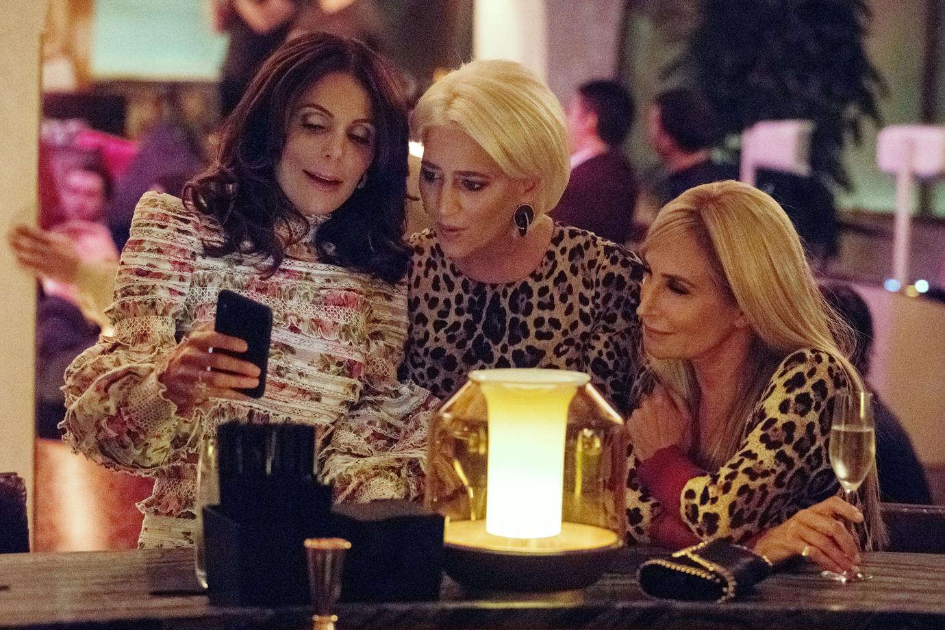 Bethenny Frankel, Dorinda Medley, Sonja Morgan At A Bar All Looking Toward A Cell Phone