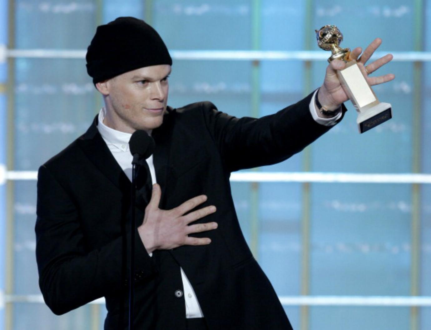 Michael C. Hall stands on stage holding a Golden Globe award.