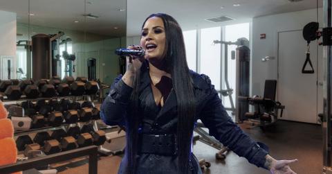 Demi Lovato performing at a concert with a gym as the background.